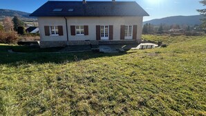 A two-story house with a sloped roof, a chimney, and a stone foundation. - Villa Le domaine des Rêves (Plateau d'Hauteville)