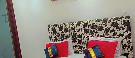 A modern bedroom with a cow print bedspread, a red blanket, and two wall-mounted flower paintings.