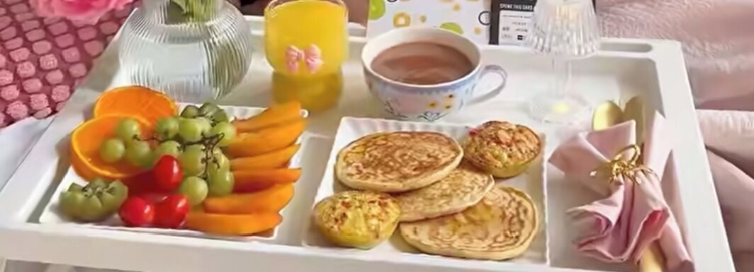 A tray with a variety of breakfast items including fruits, pastries, and a cup of coffee.