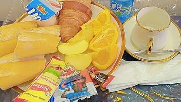 A breakfast tray with croissants, orange slices, a bottle of water, a cup, and a packet of snacks.