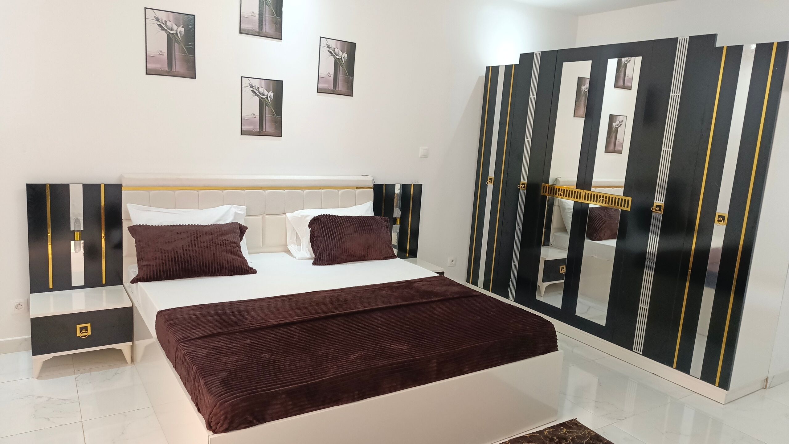 A bedroom with a bed, bedside tables, a dresser, a mirror, and artwork on the walls.