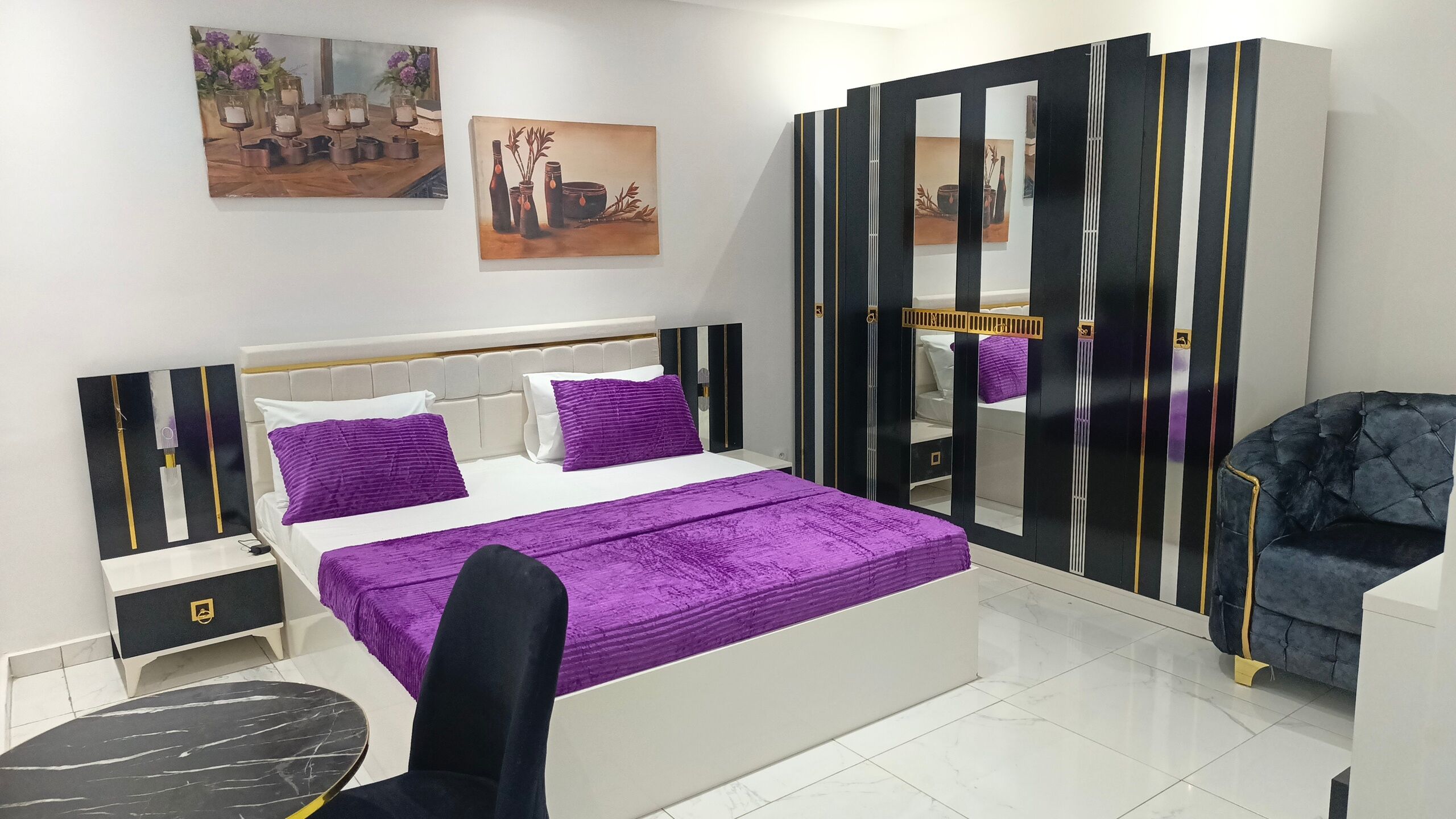 A modern bedroom with a bed, a chair, a nightstand, and a dresser.
