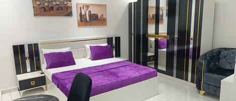 A modern bedroom with a bed, a chair, a nightstand, and a dresser.