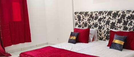 A modern bedroom with a large bed, a red and black patterned headboard, and two wall-mounted butterfly art pieces.
