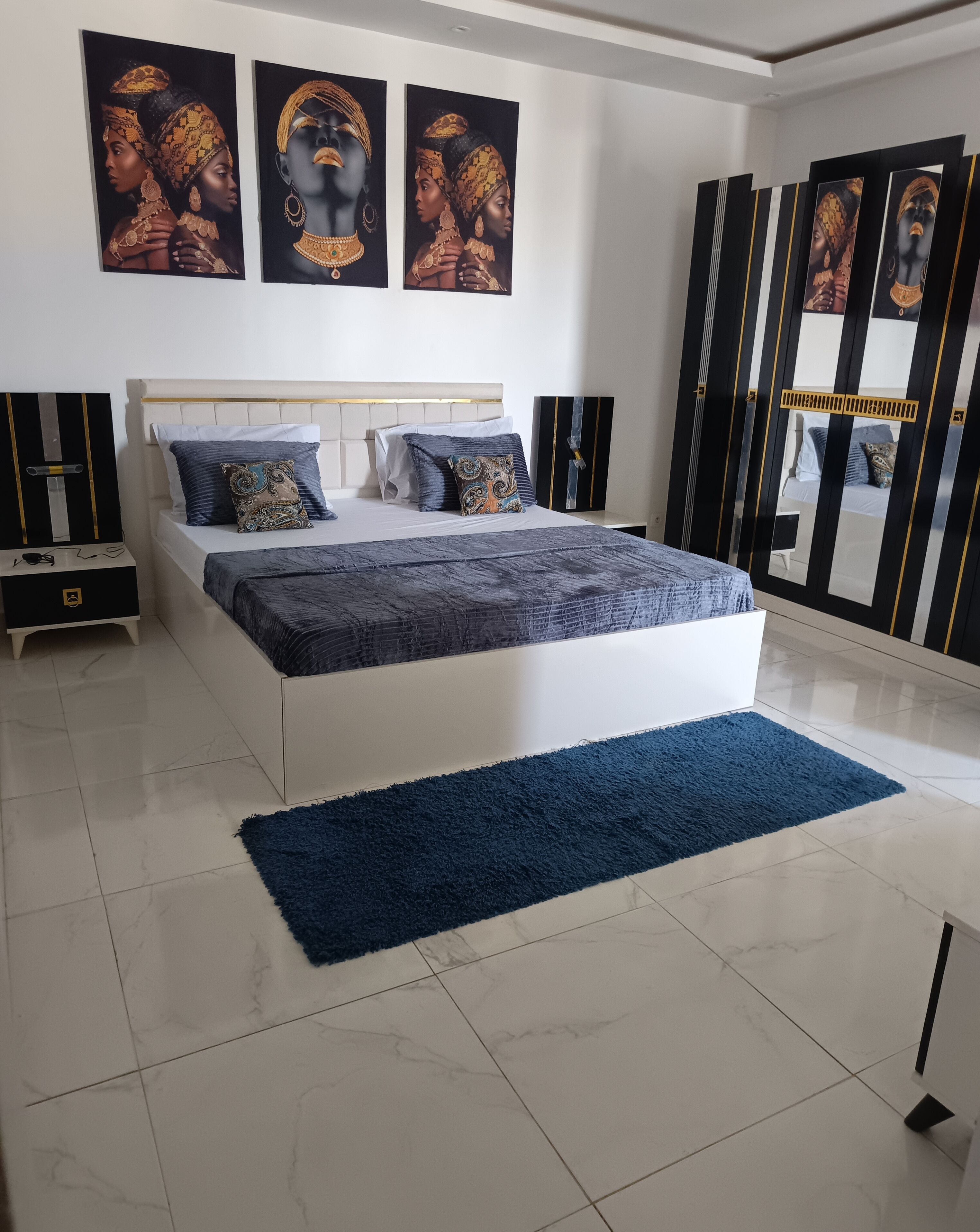 A modern bedroom with a large bed, a nightstand, a dresser, and a mirror.