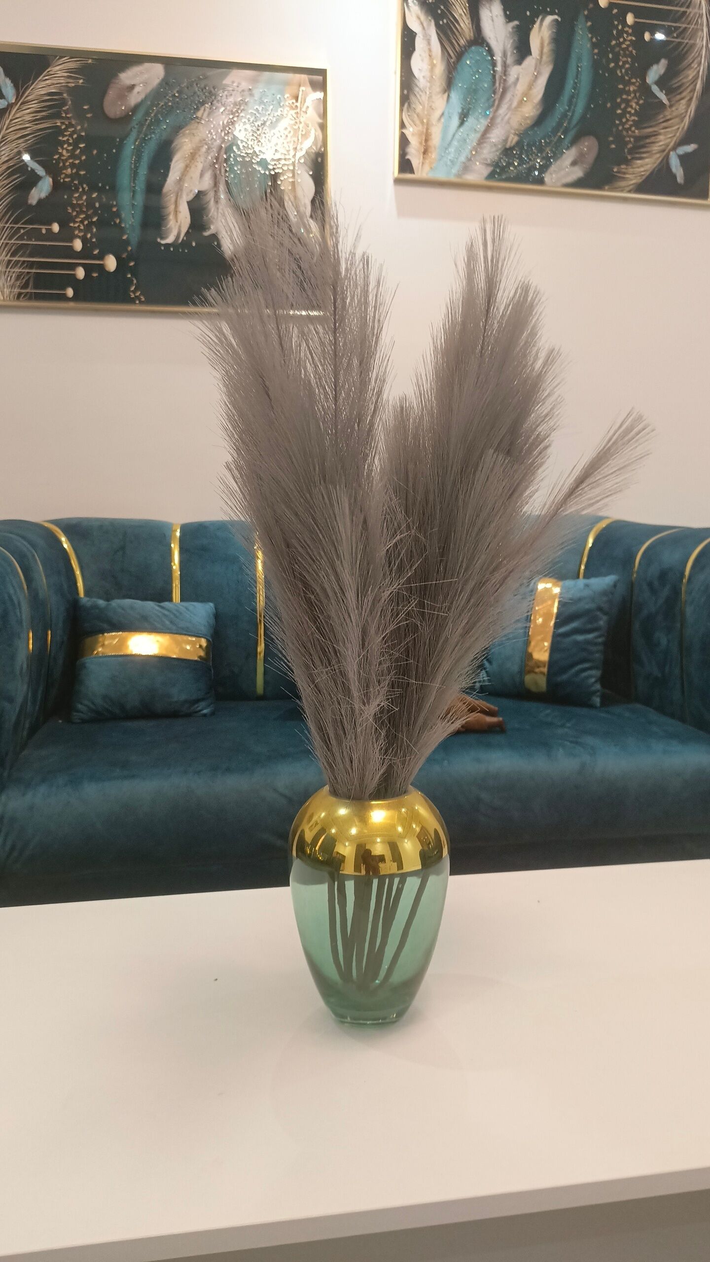 Eine grüne Vase mit goldener Kante und dekorativen Elementen auf weißem Untergrund.