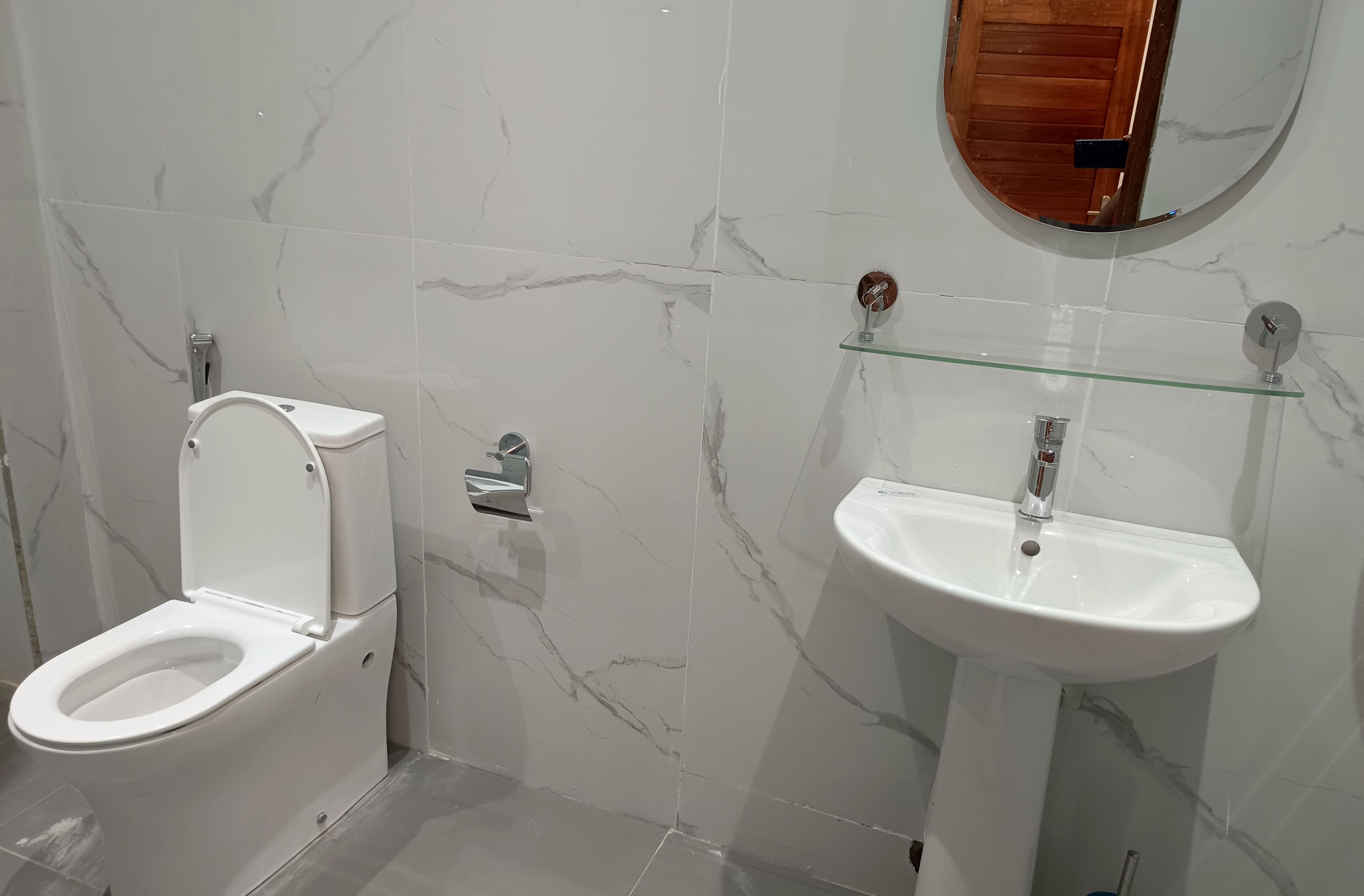 A bathroom with a toilet and a sink, both with marble-like tiles.