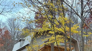 A rustic cabin with a wooden deck and a staircase leading to a second level. - One of a kind 4-bedroom barndominium in Warsaw, Ohio on 23 wooded acres. (Warsaw)