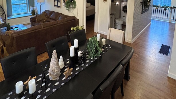 A spacious living area with a high ceiling, a dining table set with candles, and a cozy seating area with a couch and chairs. - One of a kind 4-bedroom barndominium in Warsaw, Ohio on 23 wooded acres. (Warsaw)