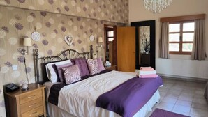 Un dormitorio con cama, mesita de noche, cómoda, candelabro y ventana con cortinas.