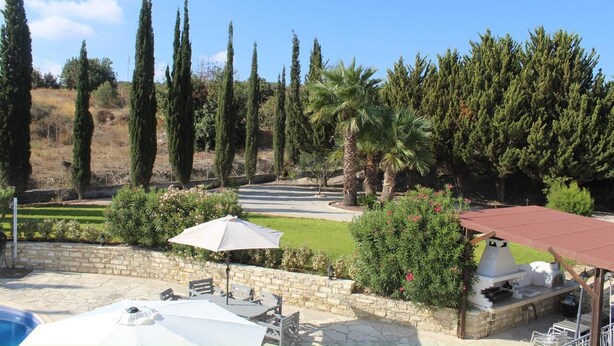 Un jardín ajardinado con piscina, mobiliario de exterior y zona de barbacoa.