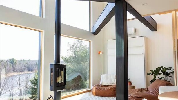 A modern interior with large windows, a fireplace, and a cozy seating area. - Lakeside Loft, Roof Deck + Sauna (Phelps)