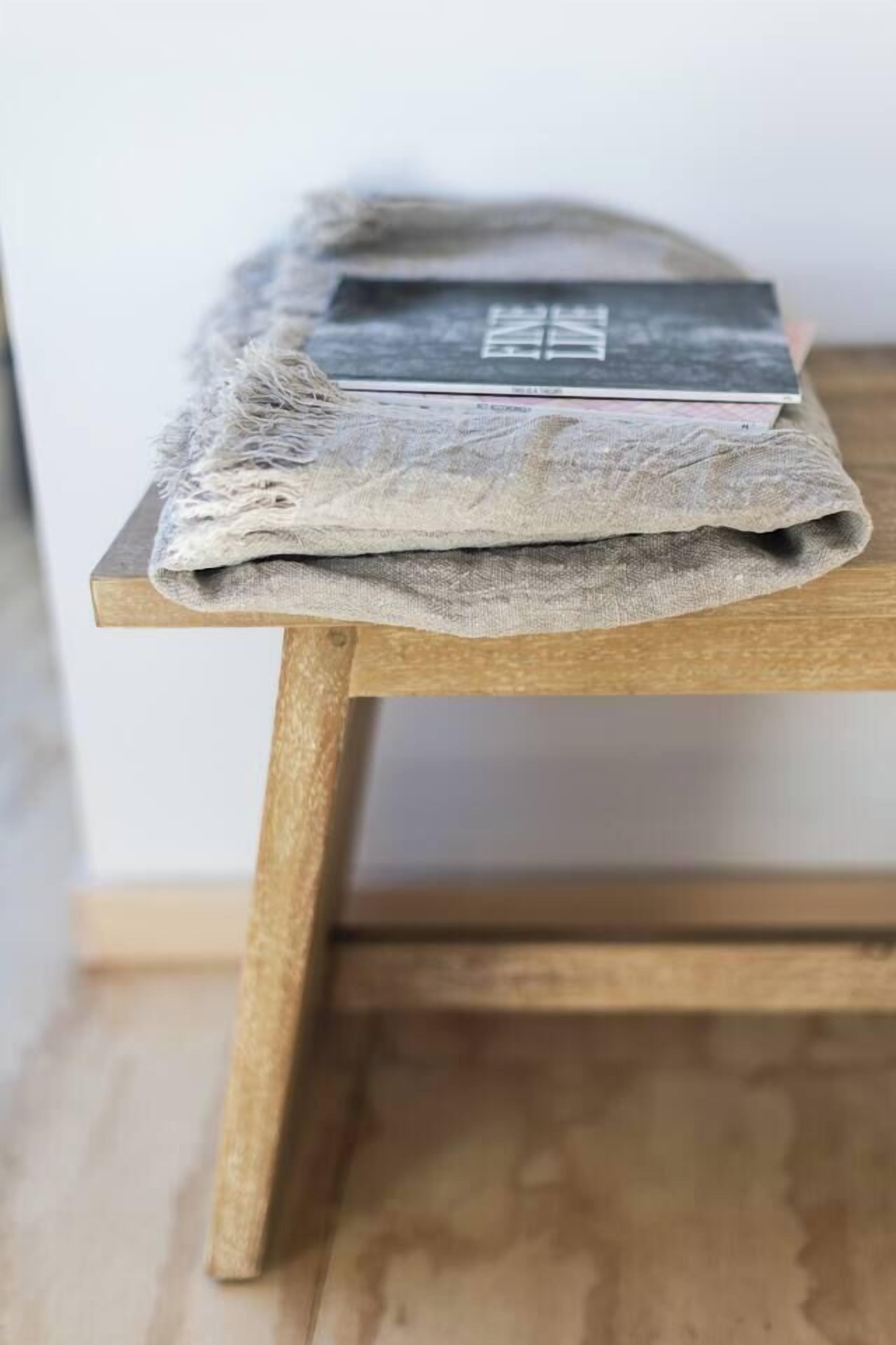 A wooden table with a folded cloth and a book on top.