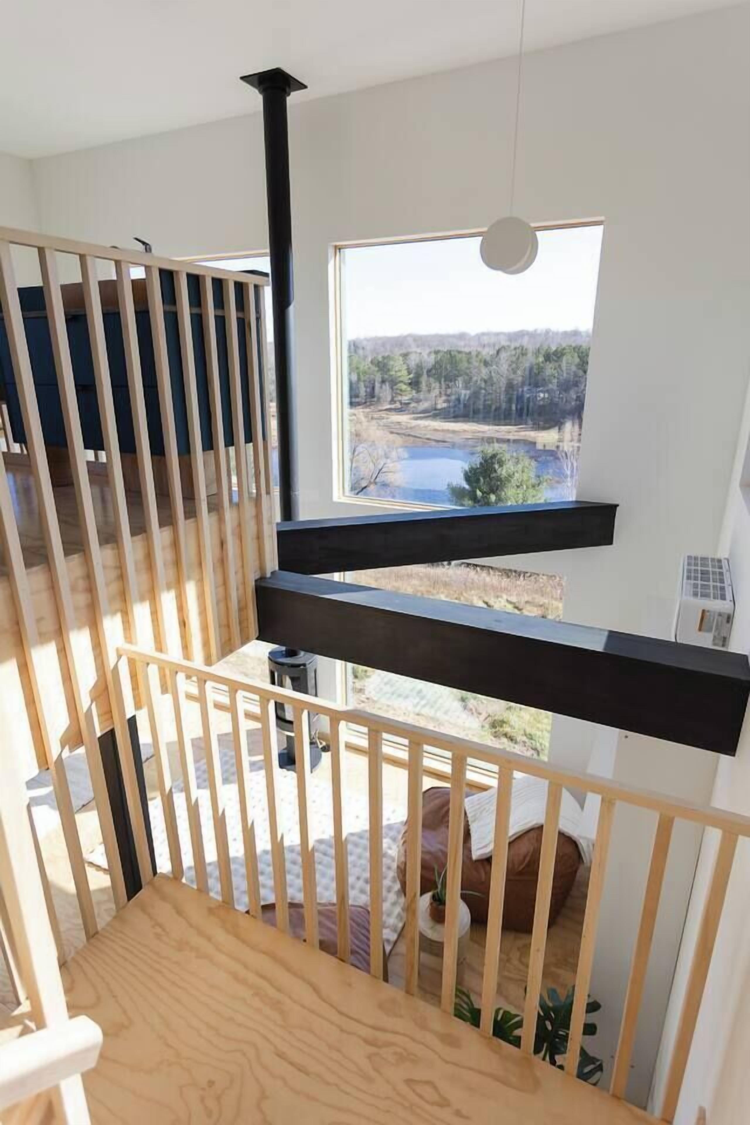 Una escalera de madera con vistas a un lago y un bosque a través de una ventana.