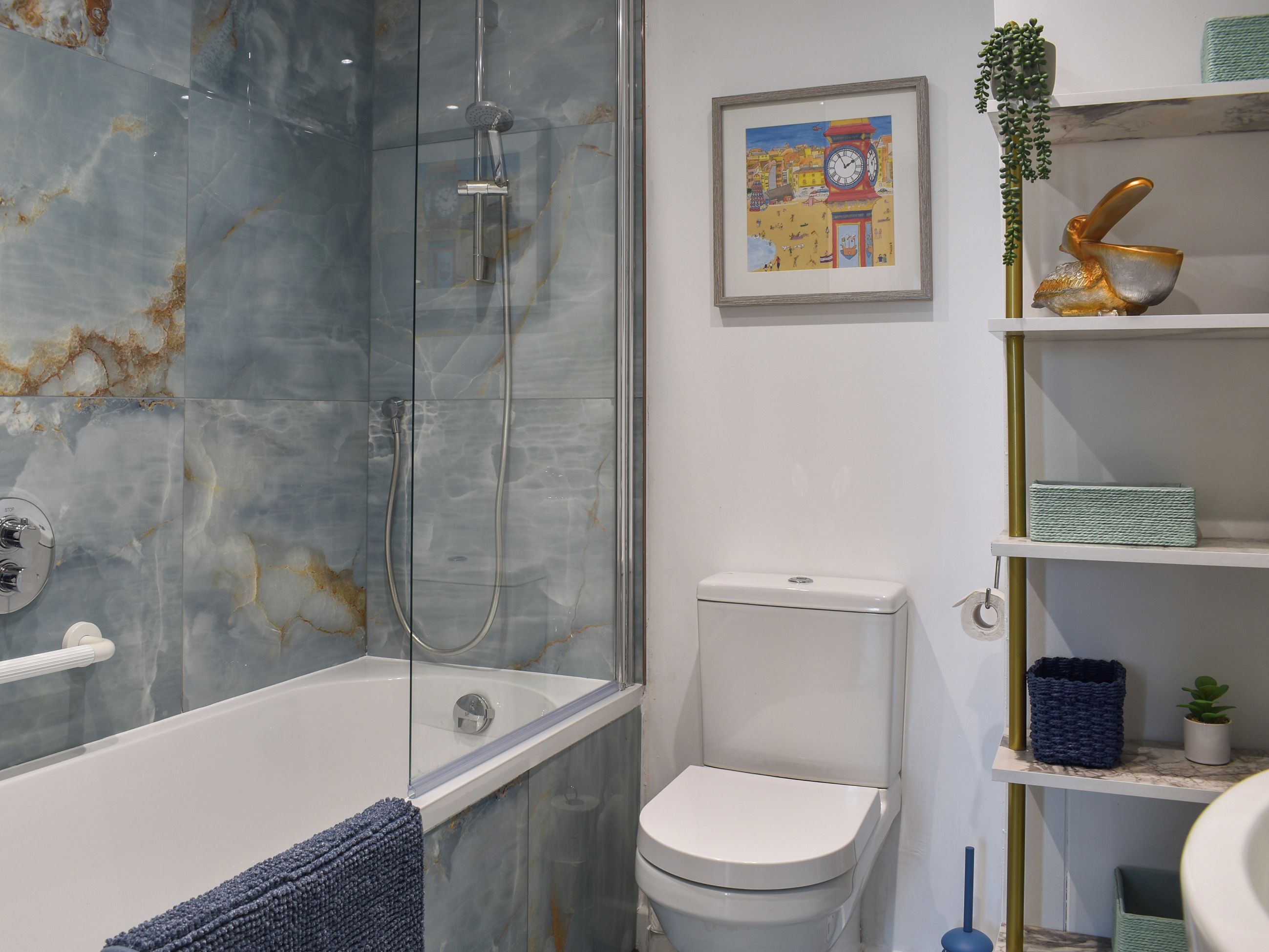 Ein Badezimmer mit einer Duschkabine, einer weißen Toilette und einem Regal mit Dekoration.
