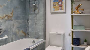 Ein Badezimmer mit einer Duschkabine, einer weißen Toilette und einem Regal mit Dekoration.