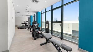 A modern gym with cardio machines, weight stations, and benches. - Urban Chic 1BR in Dubai (Dubai)
