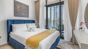 Moderni hotellihuone, jossa on suuri sänky, työpöytä ja näkymä korkeisiin rakennuksiin.