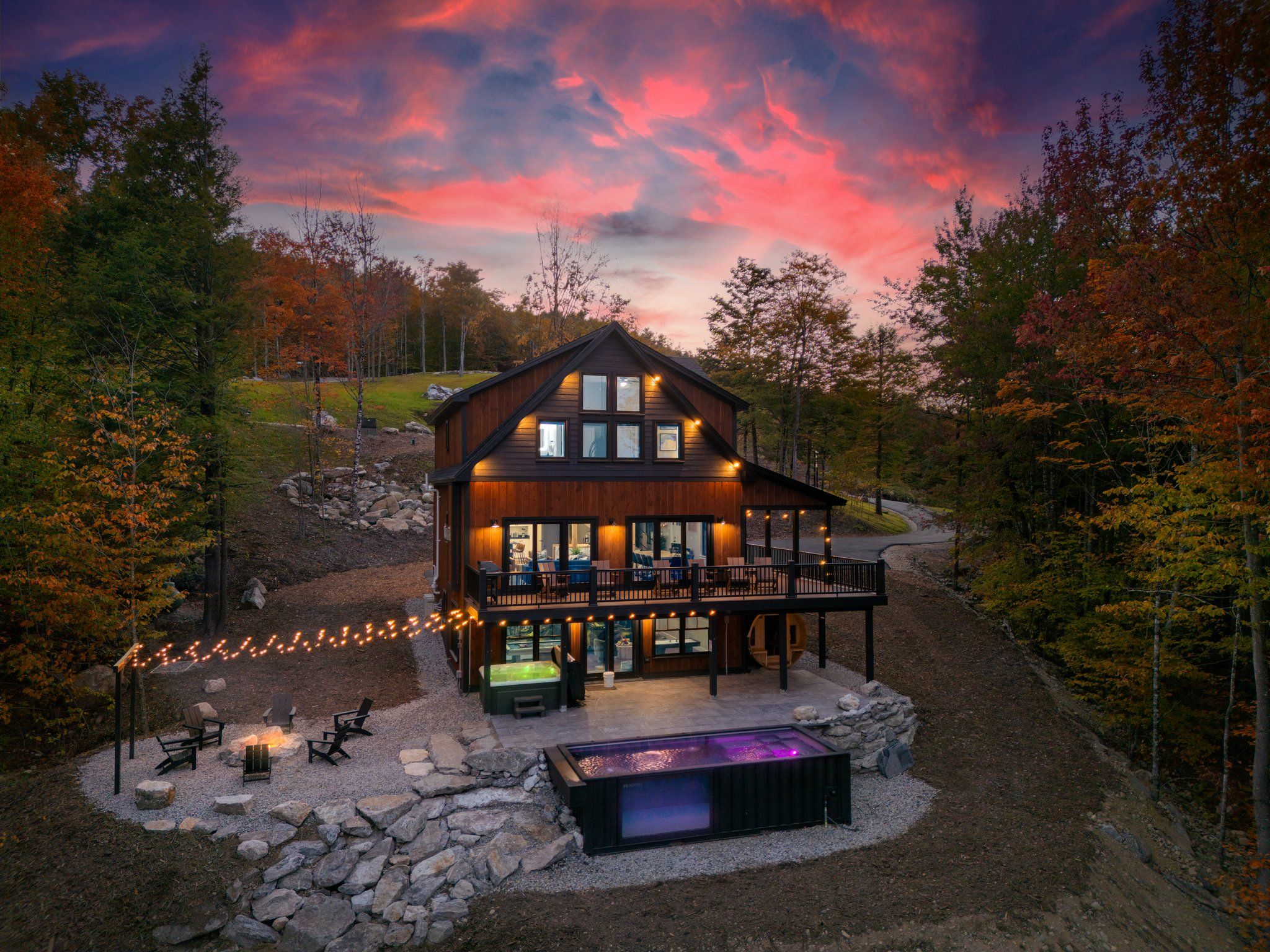 A cabin with a deck, outdoor seating, and a hot tub.