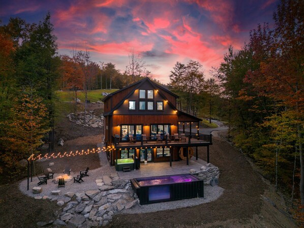 Una cabaña con terraza, asientos exteriores y un jacuzzi.
