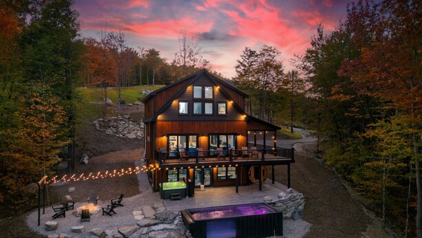 Una cabaña de madera con terraza, mobiliario exterior y jacuzzi.