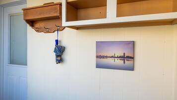 A room with a wooden coat rack, a hanging bag, and a cityscape painting on the wall.