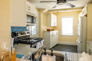 A kitchen with a stove, microwave, cabinets, and a window. - Steps from the ocean - minutes from Boston (Winthrop)