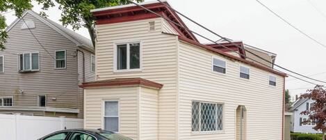 A two-story house with a garage, a car parked in front, and a bicycle lane on the street.