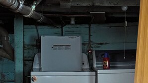 Een compacte, industriële kamer met een wasmachine en droger op een houten platform.