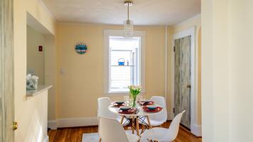 A dining area with a round table, white chairs, and a chandelier.