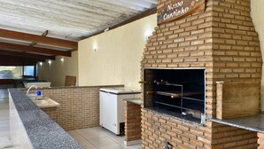 An outdoor kitchen area with a brick oven, a sink, and a countertop. - Recanto Elter (Piracaia)