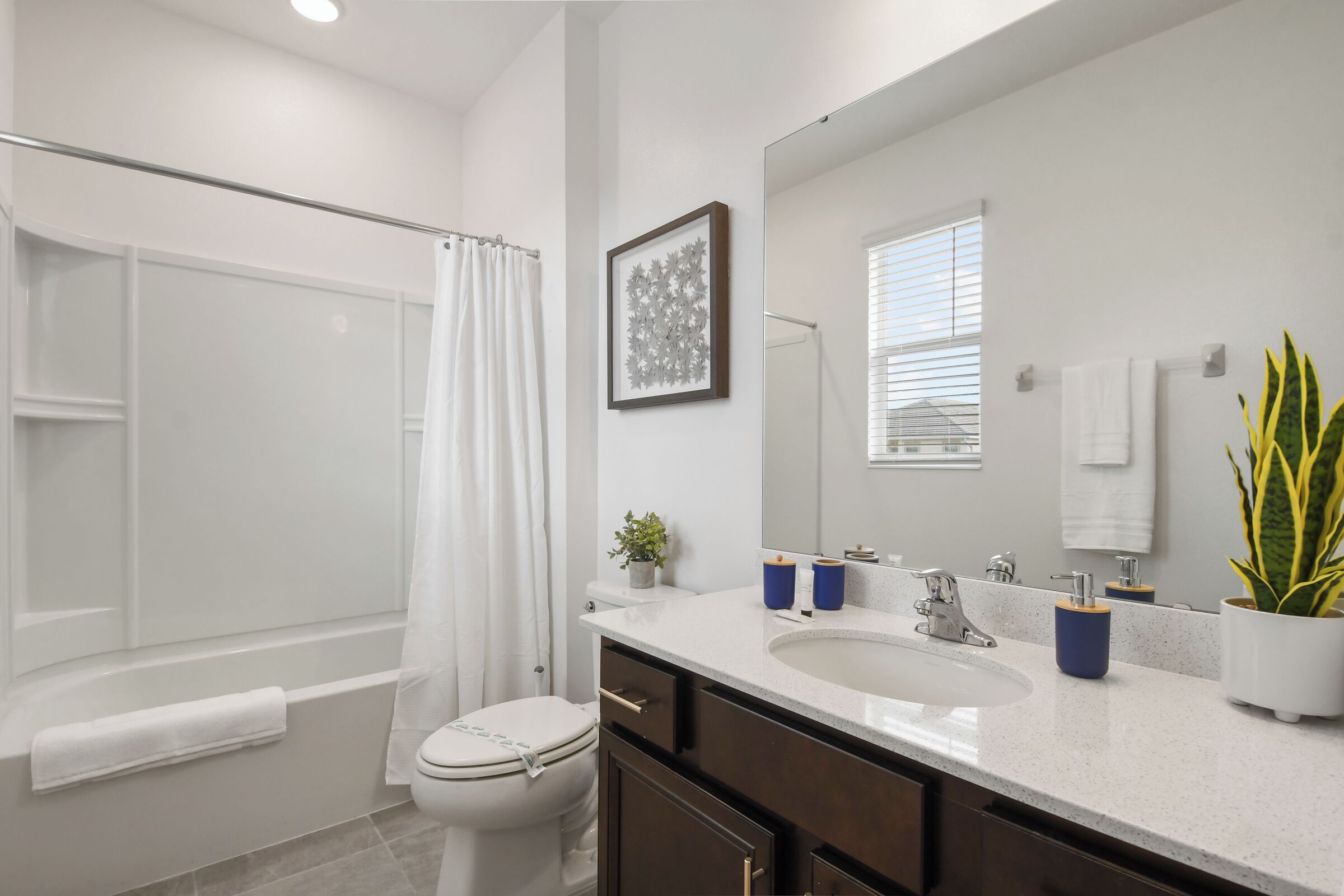 A modern bathroom with a bathtub, toilet, sink, and a large mirror.