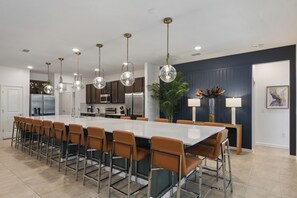 A modern kitchen with a large island, stainless steel appliances, and pendant lighting.