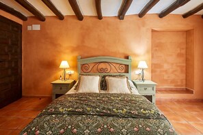 A bedroom with a bed, two bedside tables, lamps, and a wooden ceiling.
