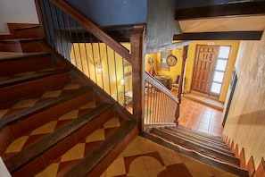 A wooden staircase with a geometric patterned floor leading to a room with a wooden door and a wall-mounted clock. - Pajarilla de Cosuenda Country House (Cosuenda)