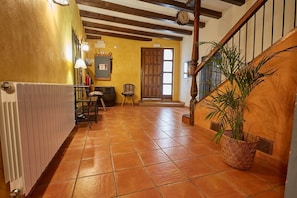 A hallway with a tiled floor, a wooden staircase, a door, and a potted plant. - Pajarilla de Cosuenda Country House (Cosuenda)