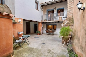 A courtyard with a dining table and chairs, a potted plant, and a small table with a chair. - Pajarilla de Cosuenda Country House (Cosuenda)