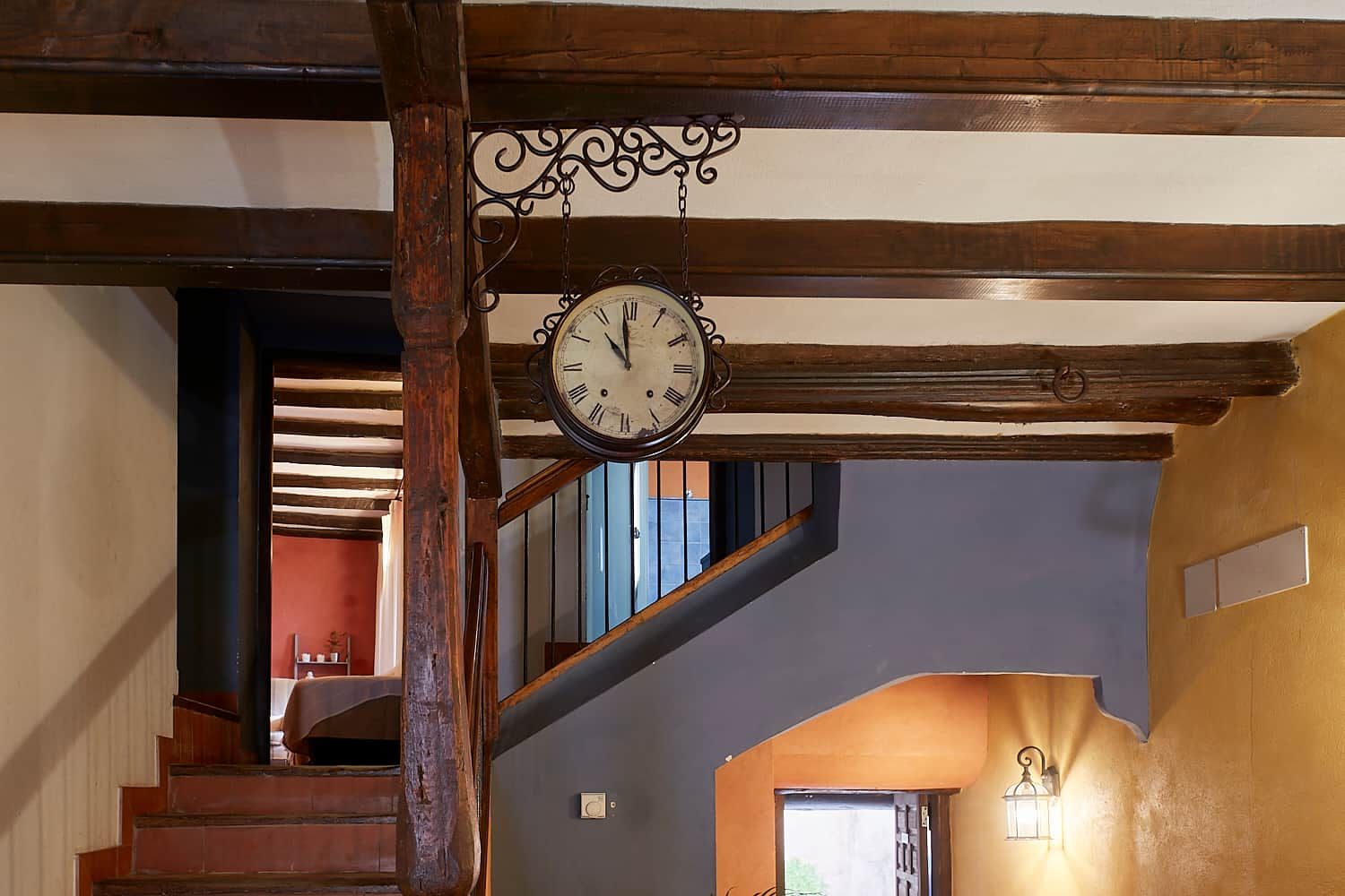 Un escalier en bois avec une horloge murale suspendue.