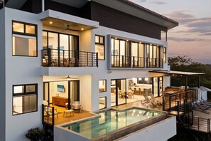 A modern two-story house with a swimming pool, outdoor seating, and a balcony. - Casa Sol: Luxury 4 BR, Ocean View Villa-Pool & Concierge - Playa Hermosa (Playa Hermosa)
