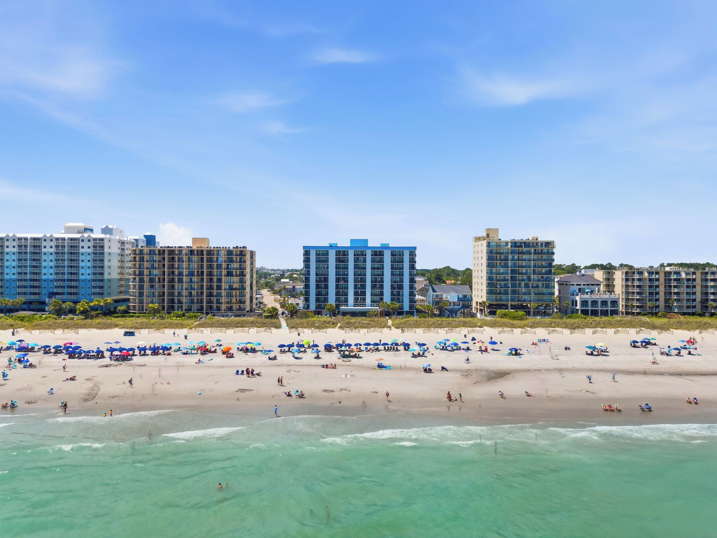 A beach with multiple hotel buildings in the background.