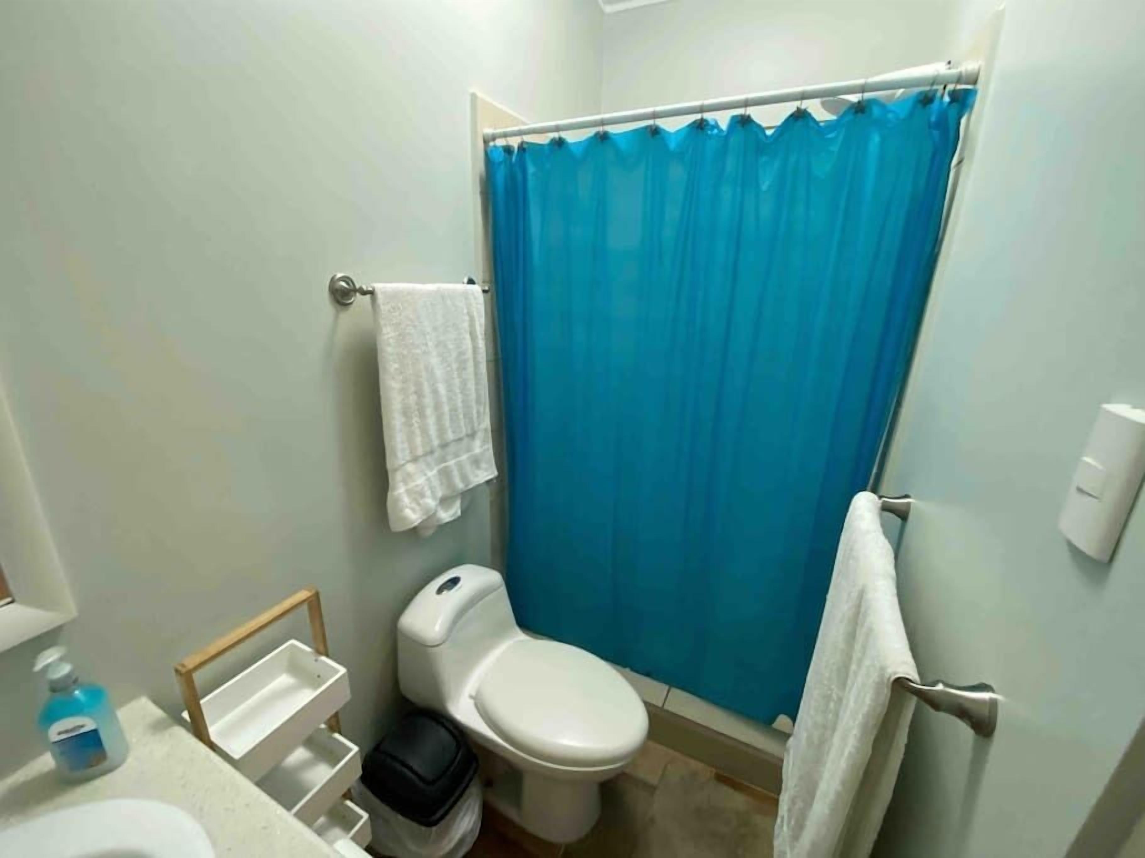 Ein kleines Badezimmer mit Toilette, Waschbecken, Duschvorhang und Handtuchhalter.