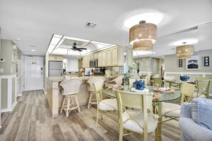 A modern kitchen with a central island, bar stools, and a dining area with round tables and chairs. - 705 is a Cozy 2-bedroom 7th floor condo in beautiful Daytona Beach Shores. (Daytona Beach)