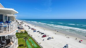 Een strandhotel met een zwembad, ligbedden, parasols en uitzicht op zee.