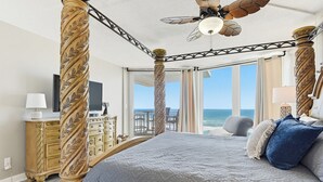 Een hemelbed met een plafondventilator, een televisie en uitzicht op de oceaan.