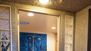 A doorway with a 'Welcome' mat, a blue abstract painting on the wall, and a textured wall with a window. - Charming 2-bedroom condo with AC and WiFi in delightful Palm Desert (Palm Desert)