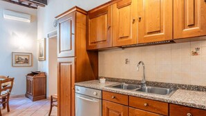 Una cucina con mobili in legno, un lavello in acciaio inossidabile e una lavastoviglie.