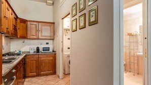 Una cucina compatta con mobili in legno, un forno a microonde e una lavatrice.