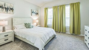Ein Schlafzimmer mit einem Bett, Nachttischen, einer Kommode und Bildern an den Wänden.