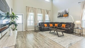 Ein geräumiges Wohnzimmer mit einem Ecksofa, einem Couchtisch und einem großen Fenster.