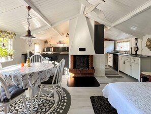 A cozy interior with a dining area, a fireplace, a kitchen, and a bed.